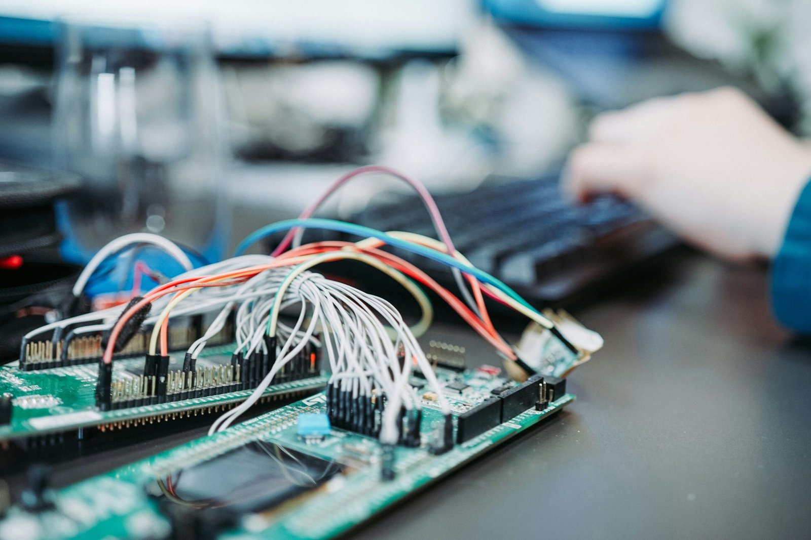 person using computer keyboard near green circuit board